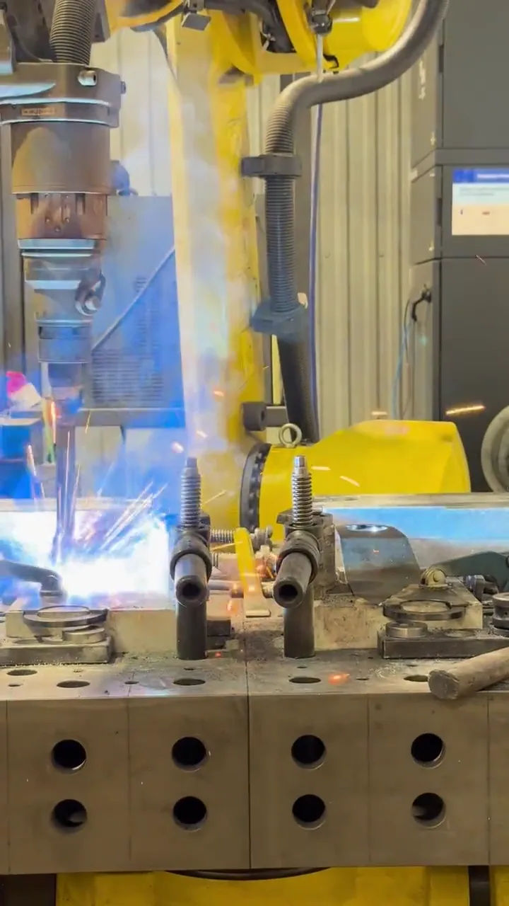 Gros plan sur la torche d'un robot de soudage FANUC pendant le soudage