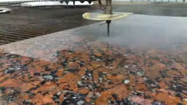 Buse de découpe au jet d'eau au-dessus d'une dalle de granit rouge, extrait d'une vidéo de 2009.