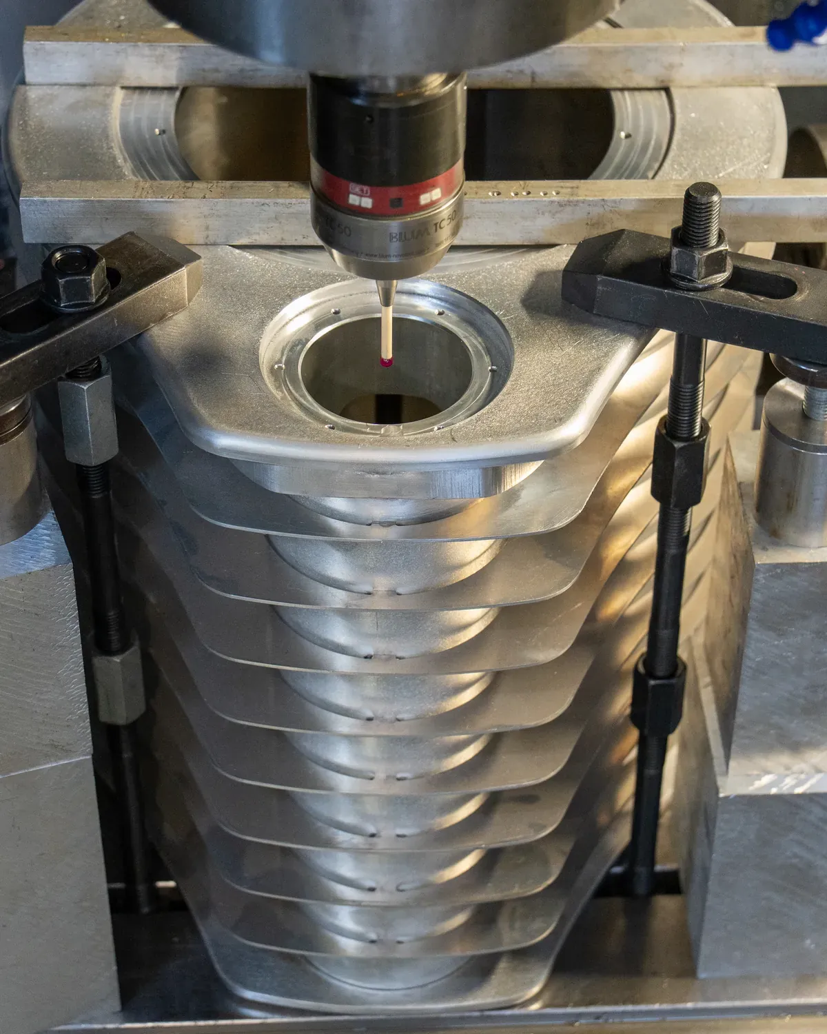 Vue de dessus : palpeur de mesure à bille en rubis engagé dans l'alésage d'une pièce en aluminium nervurée, maintenue par des brides.
